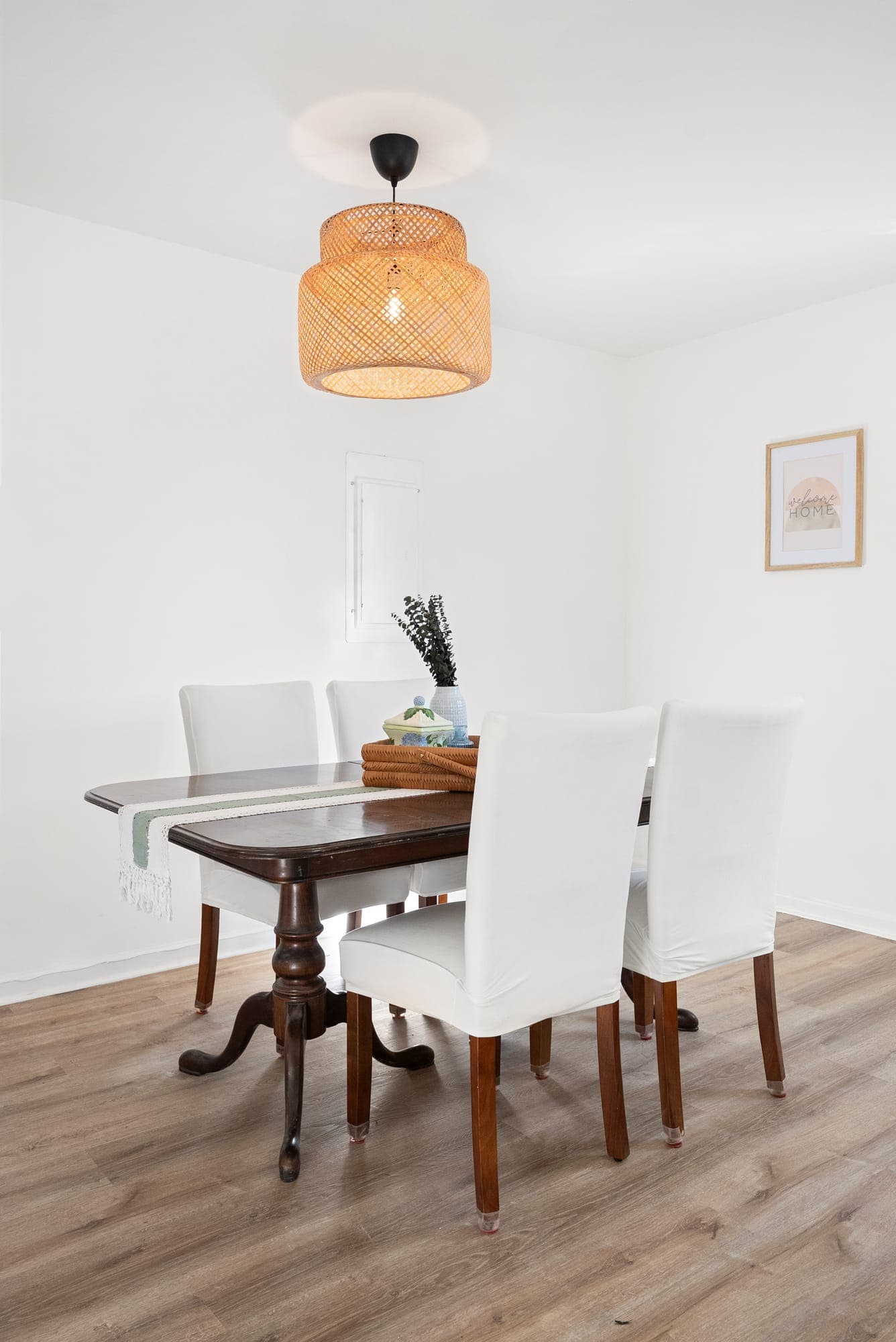 Dining room with new wood-look plank flooring, white walls and a woven rattan pendant light