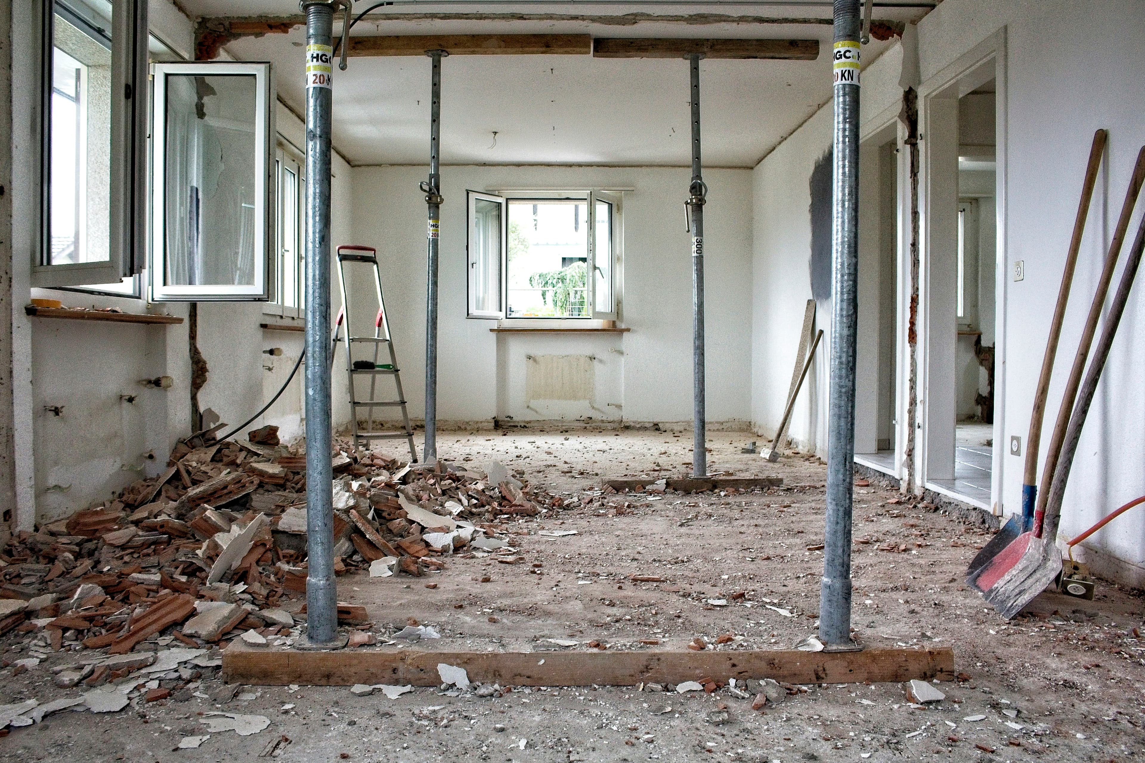 Room stripped to the studs with temporary support posts and debris on the floor