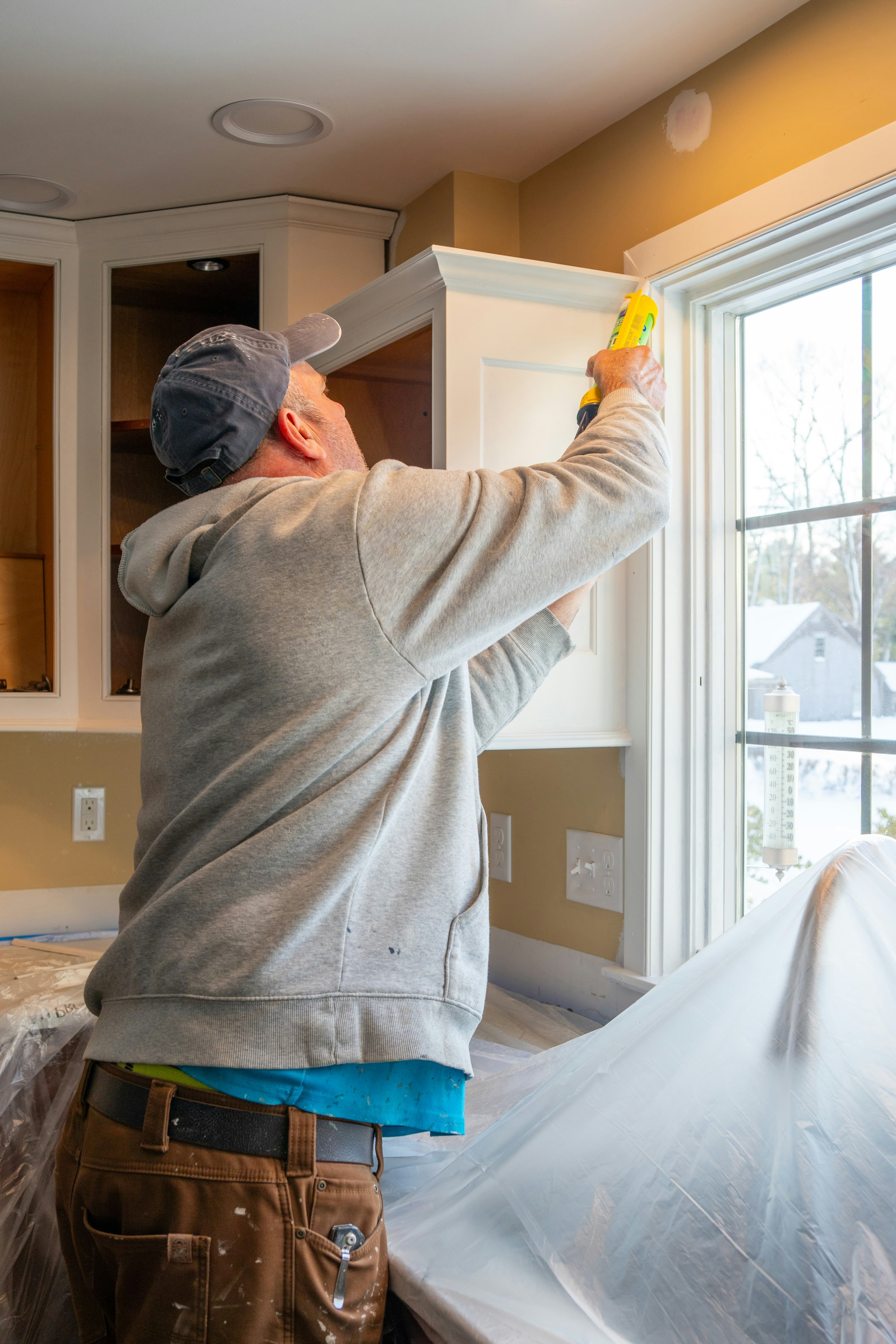 Installer sealing the frame of a newly installed kitchen window